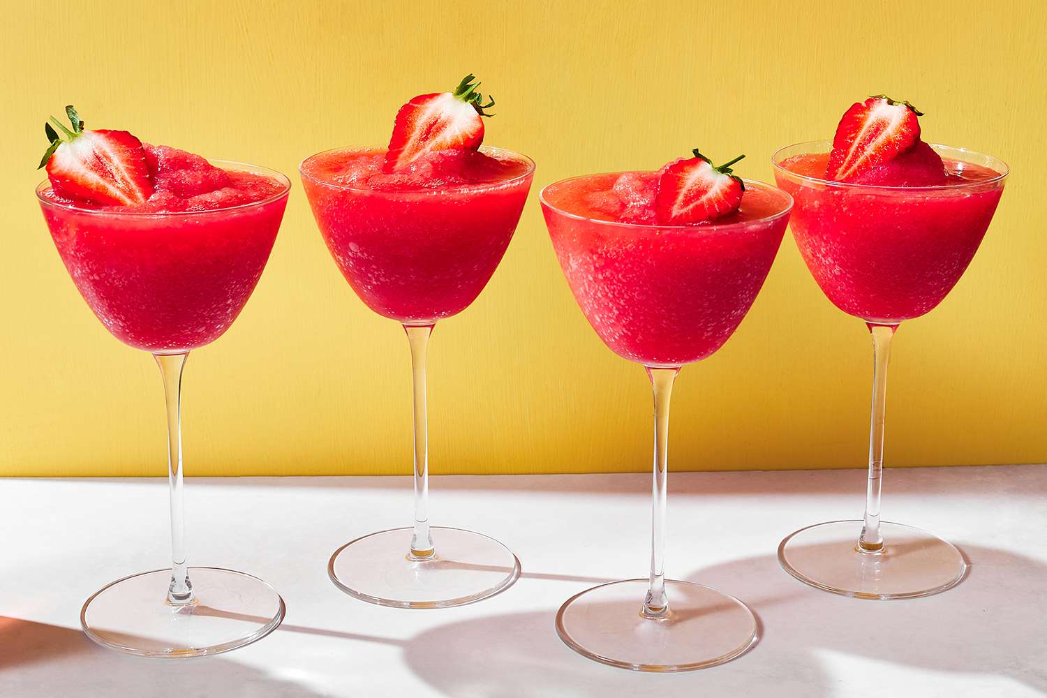 Four glasses of frose garnished with strawberries