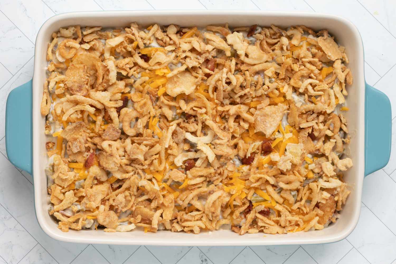 bacon and cheddar green bean casserole is topped with crispy french fried onions