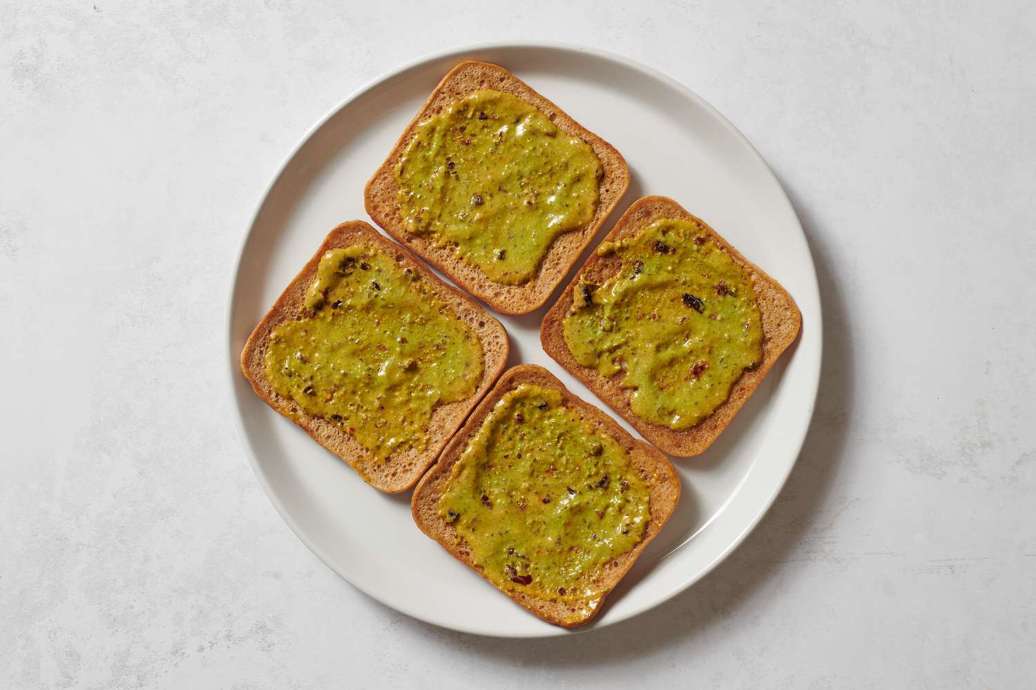 Four slices of bread topped with spicy pesto aioli
