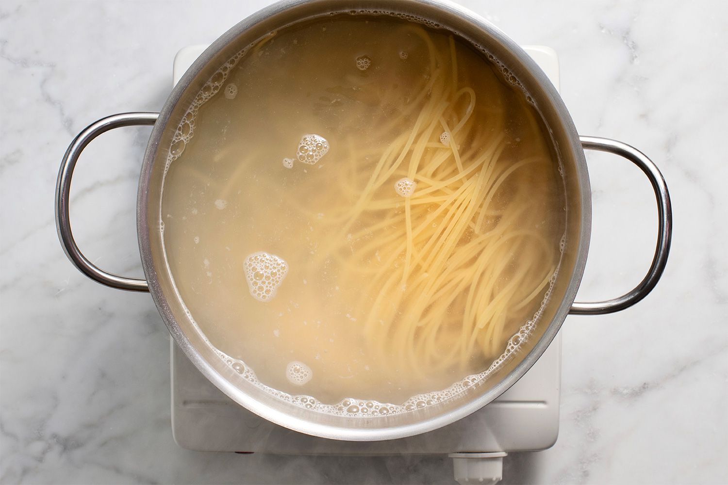 Pasta and water in a pot on a burner 