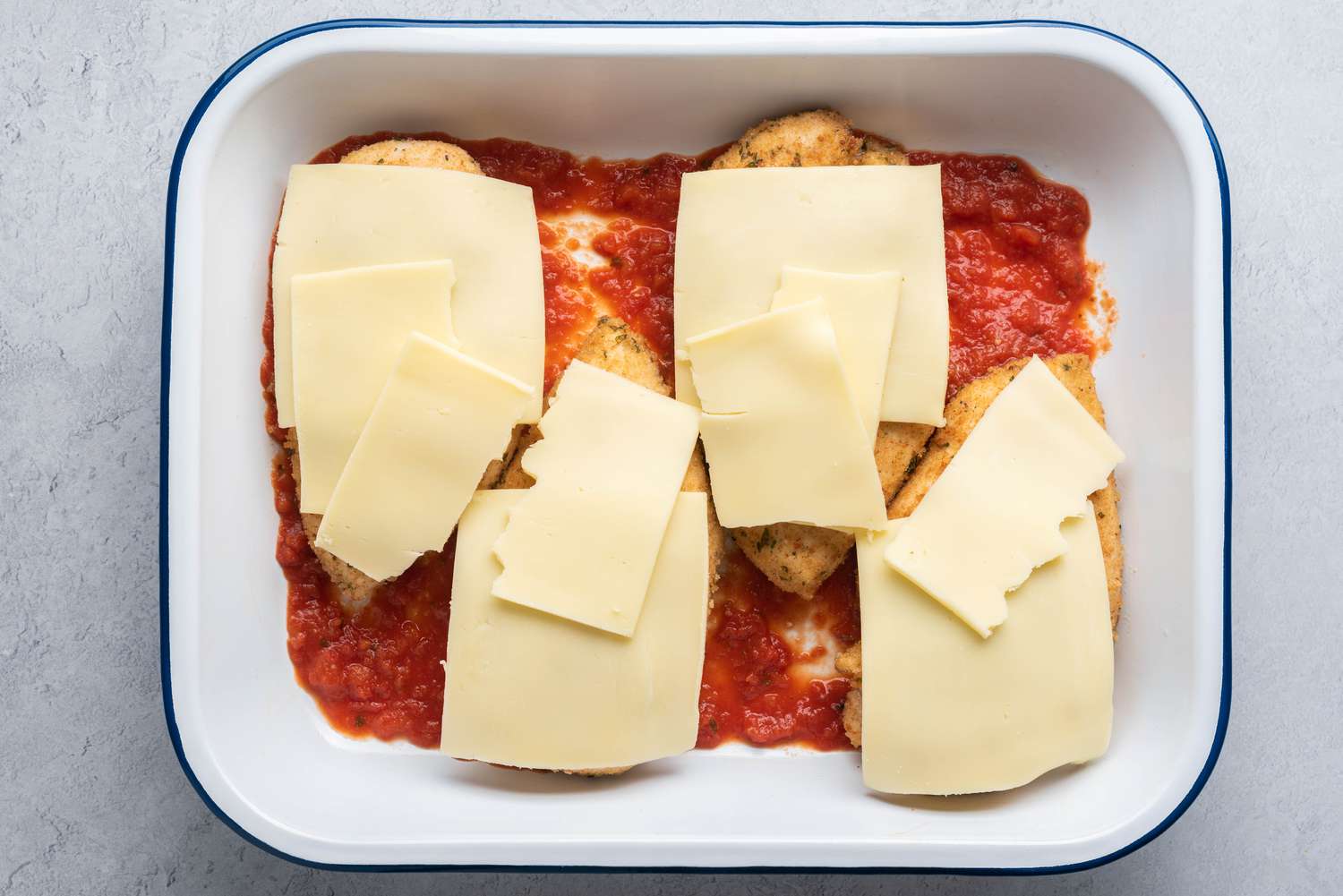 Tomato sauce, chicken and cheese in a greased casserole dish 