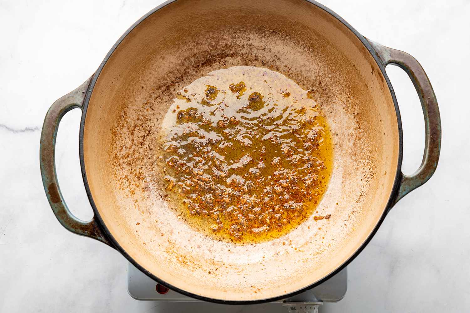 Anchovies and crushed red pepper in a pot on a burner 