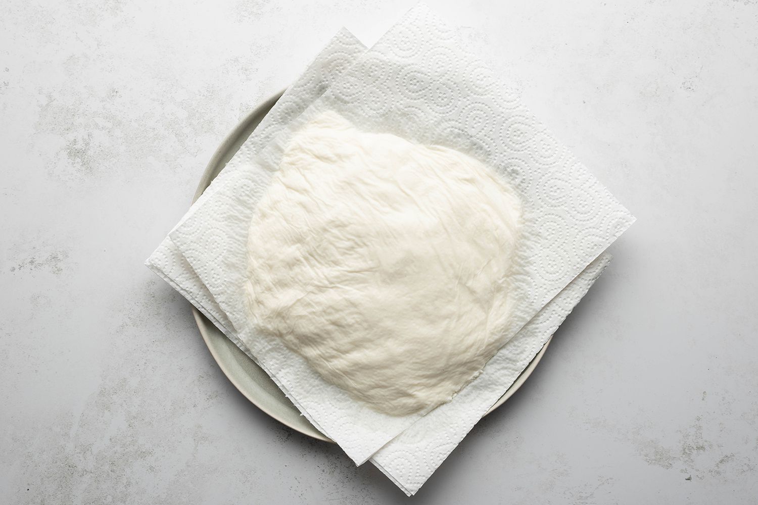 Ricotta cheese between paper towels on a plate 
