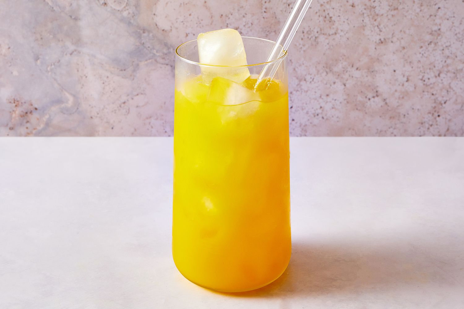 Orange juice, tequila, and ice stirred together in a cocktail glass