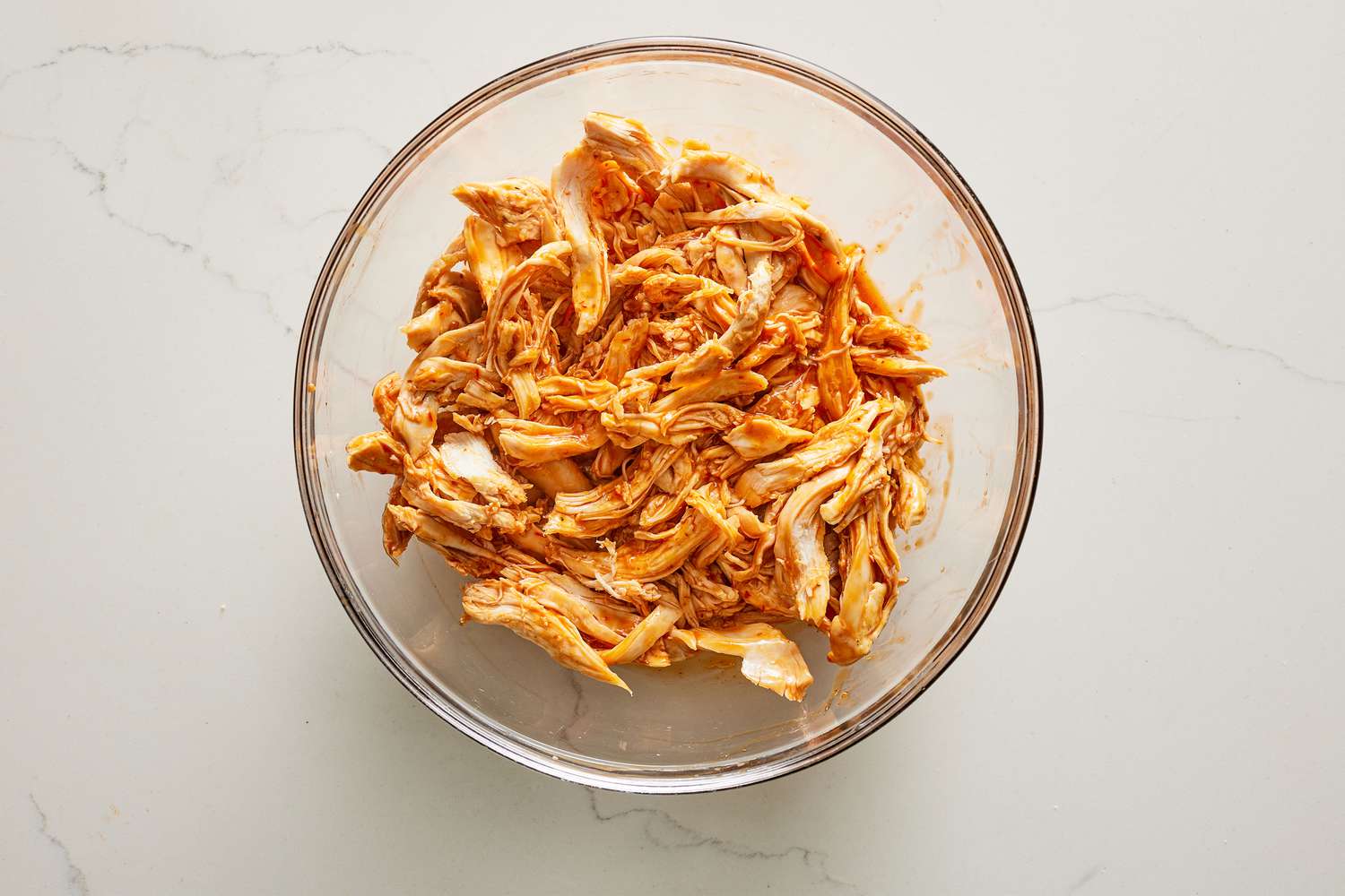 A bowl of shredded chicken tossed in honey-chile sauce